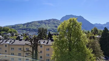Panoramablick auf die umliegende Berglandschaft und Wohngebäude unter blauem Himmel.