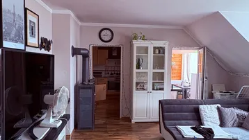 Wohnzimmer mit Fernseher, Kaminofen und Zugang zu weiteren Räumen.