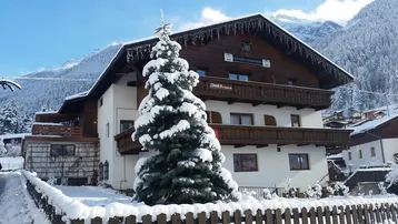 Traditionelles Chalet im Winter, umgeben von Schnee und mit Blick auf die Berge.