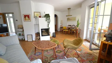 Offener Wohn-Essbereich mit modernem Kamin, Holzboden und Zugang zur Terrasse.