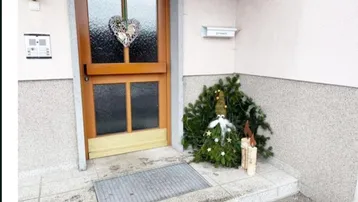 Eingangsbereich eines Gebäudes mit Holztür und festlicher Weihnachtsdekoration auf der Veranda.