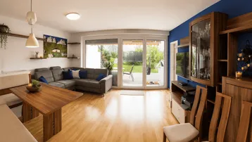 Geräumiger Wohn-Essbereich mit Holzboden, gemütlichem Sofa und Zugang zur Terrasse.