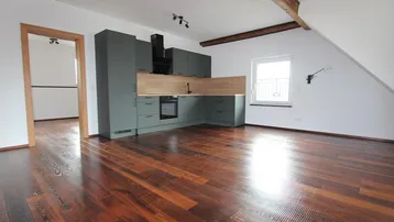 Moderne Küche in Dunkelgrau mit Holzakzenten und dunklem Parkettboden in einem offenen Wohnbereich.