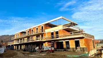 Neubau im Rohbauzustand mit sichtbaren Ziegelwänden und Gerüst unter blauem Himmel.