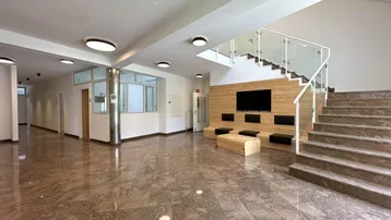 Geräumiger Eingangsbereich mit Marmorboden, moderner Treppe und Sitzgelegenheiten für Besucher.