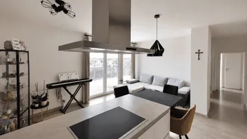 Heller, offener Wohn- und Essbereich mit moderner Küche, Kochinsel und Zugang zur Terrasse.