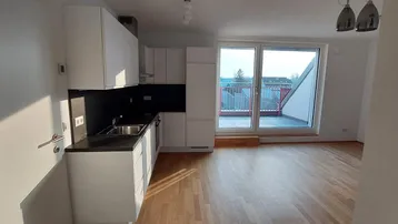 Heller offener Wohn- und Essbereich mit moderner Einbauküche, Parkettboden und Zugang zur Terrasse.