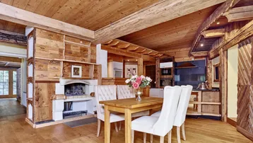 Geräumiger Wohn-Essbereich mit Kamin, Holzbalken und Esstisch im alpinen Landhausstil.