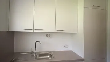 Moderne Einbauküche mit weißen Schränken, Spüle und Kochfeld.
