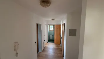 Heller Flur mit Laminatboden und mehreren Türen, der zu weiteren Räumen führt.