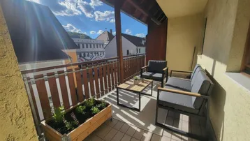 Sonniger Balkon mit bequemen Gartenmöbeln und Blick auf die umliegenden Gebäude.