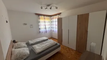 Gemütliches Schlafzimmer mit Doppelbett, Holzschrank und Parkettboden, ideal für erholsame Nächte.
