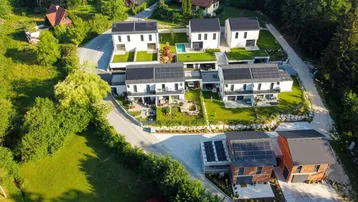 Luftaufnahme einer modernen Wohnsiedlung mit mehreren Häusern, Gärten und einem Pool.
