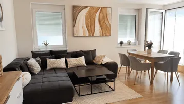 Heller Wohn- und Essbereich mit großem Ecksofa, Esstisch und Zugang zur Terrasse.