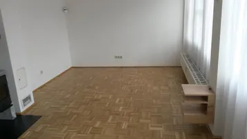 Geräumiges Wohnzimmer mit Parkettboden, großen Fenstern und viel Tageslicht.