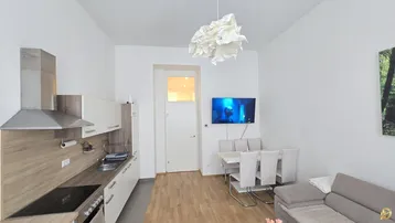 Moderne Wohnküche mit Essbereich und Sofa, ausgestattet mit hellen Möbeln und Holzboden.