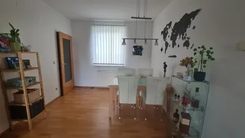 Heller Essbereich mit Holzboden, modernem Esstisch und dekorativer Weltkarte an der Wand.