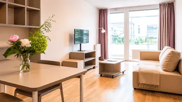Helles Wohn- und Esszimmer mit Holzboden, Balkonzugang und moderner Einrichtung.
