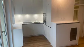 Moderne weiße Einbauküche mit Holzfußboden und integrierten Geräten.