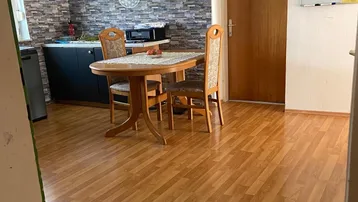 Funktionale Küche mit Essbereich, dunklen Schränken, Laminatboden und dekorativer Wandverkleidung.