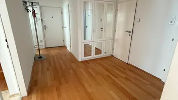 Heller Flur mit Holzparkettboden und einem praktischen Einbauschrank mit Spiegeltüren.