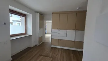 Heller Raum mit Einbauschränken, Holzboden und Fenster mit Blick nach draußen.