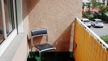 Kleiner Balkon mit Kunstrasen und einem Stuhl, bietet Blick auf den Außenbereich.