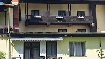 Detailansicht der Hotelrückseite mit Balkonen, einer Holzterrasse und Solarpaneelen auf dem Dach.