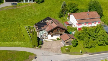 Luftaufnahme des Anwesens mit Wohnhaus, Nebengebäude, Garten und Photovoltaikanlage auf dem Dach.