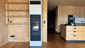 Offener Wohnbereich mit Holzboden, Kamin und integrierten Holzregalen.