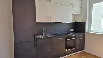Moderne Einbauküche mit dunklen Unterschränken, weißen Oberschränken und integrierten Geräten.