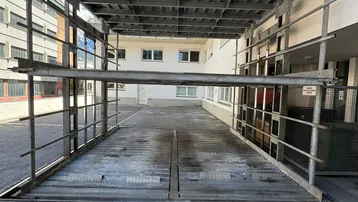 Außenansicht eines mechanischen Parkliftsystems für Fahrzeuge vor einem Wohngebäude.