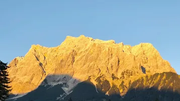 Majestätischer Bergblick bei Sonnenaufgang oder Sonnenuntergang, der die Gipfel in goldenes Licht taucht.
