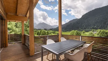 Große Holzterrasse mit Esstisch und Stühlen, bietet einen atemberaubenden Blick auf die umliegende Berglandschaft.