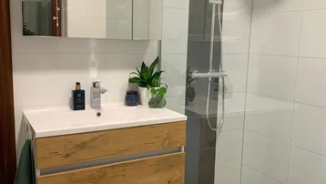Modernes Badezimmer mit schwebendem Holzwaschtisch, Spiegelschrank und ebenerdiger Regendusche.