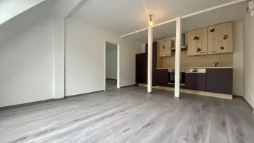 Helles Dachgeschosszimmer mit integrierter Küchenzeile und modernem Laminatboden in offener Gestaltung.