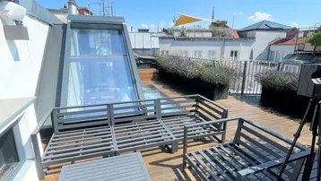 Geräumige Dachterrasse mit modernen Loungemöbeln, Holzdeck und Blick über die Stadt.