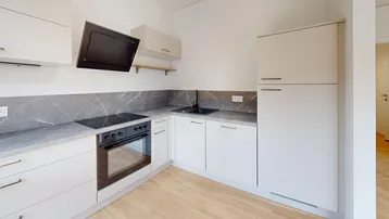 Moderne Einbauküche mit hellen Schränken, dunkler Arbeitsplatte und integrierten Geräten in neuwertigem Zustand.