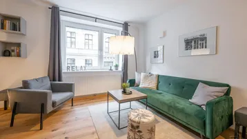 Helles Wohnzimmer mit modernem Sofa, Holzboden und Blick auf die Stadt durch das Fenster.