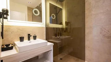 Modernes Badezimmer mit begehbarer Dusche, Einzelwaschbecken und beleuchtetem Spiegel.