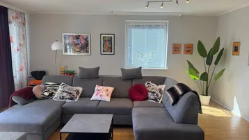 Gemütliches Wohnzimmer mit großem Ecksofa, Holzboden und farbenfrohen Akzenten.