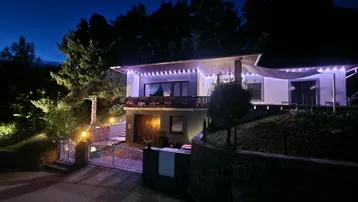 Modernes Haus bei Nacht mit festlicher Beleuchtung und gepflegtem Eingangsbereich.