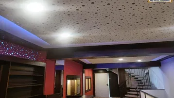 Geräumiger Innenbereich mit moderner Deckenbeleuchtung, Holzdetails und einer Treppe.