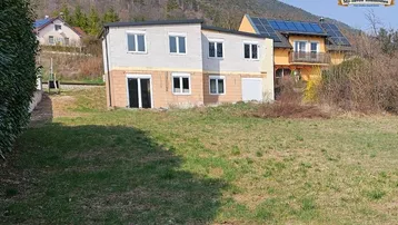 Rohbau eines Einfamilienhauses in ländlicher Umgebung mit Blick auf die Berge.