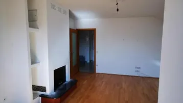 Geräumiges Wohnzimmer mit hellem Parkettboden und einem modernen Kamin, bereit zur individuellen Gestaltung.