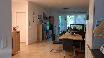 Geräumiger offener Wohn- und Essbereich mit hellem Laminatboden und großem Aquarium.