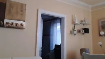 Helles Wohnzimmer mit beigen Wänden, weißem Sofa und dekorativer Deckenleiste.