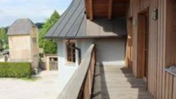 Hölzerner Balkon mit Geländer und Blick auf ein historisches Gebäude im Hintergrund.