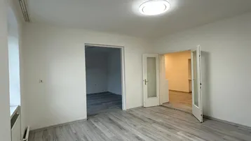 Helles Zimmer mit modernem grauem Laminatboden und weißen Wänden, bereit zur individuellen Gestaltung.