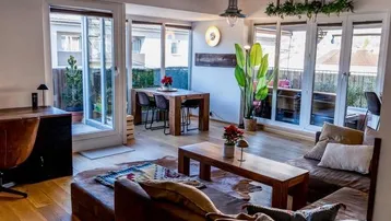 Heller Wohn- und Essbereich mit Holzboden, gemütlichem Sofa und Zugang zu einem Balkon.